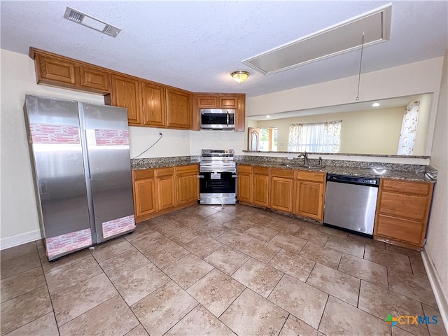 kitchen with a textured ceiling, sink, and stainless steel appliances