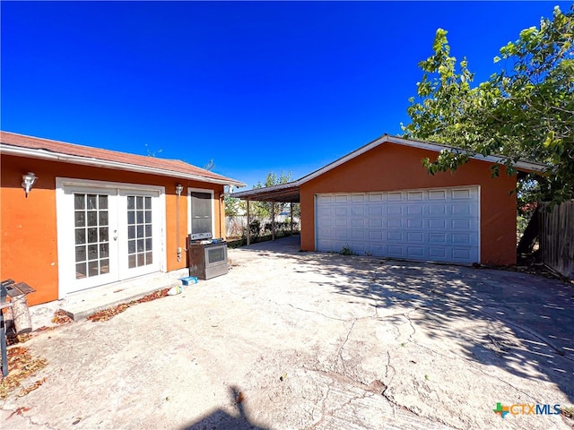 exterior space featuring a garage, a carport, and french doors