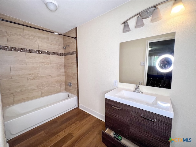 bathroom with tiled shower / bath combo, vanity, and hardwood / wood-style flooring