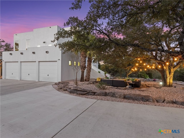 view of front of home with stucco siding, driveway, and outdoor lounge area