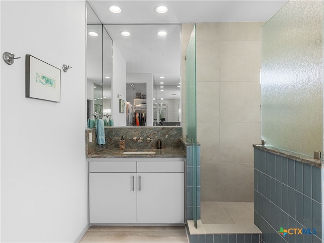 full bath featuring backsplash, wood finished floors, recessed lighting, walk in shower, and vanity