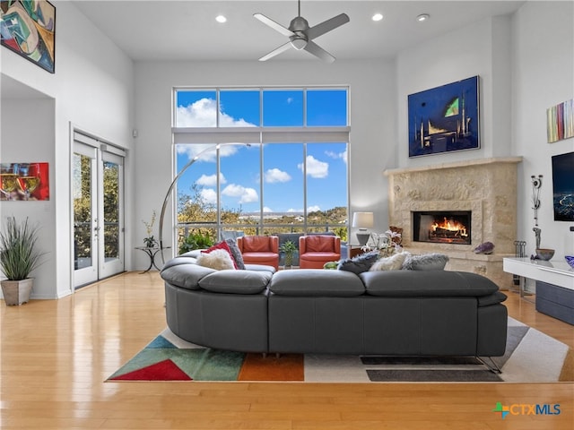 living area featuring a high end fireplace, plenty of natural light, a towering ceiling, and wood finished floors