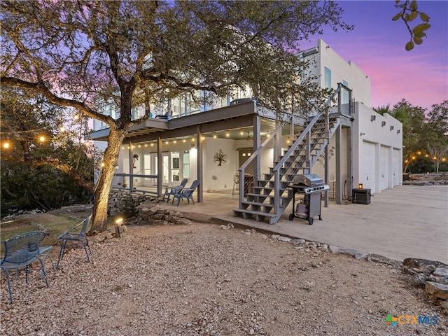 rear view of house featuring stairway, stucco siding, driveway, and a patio