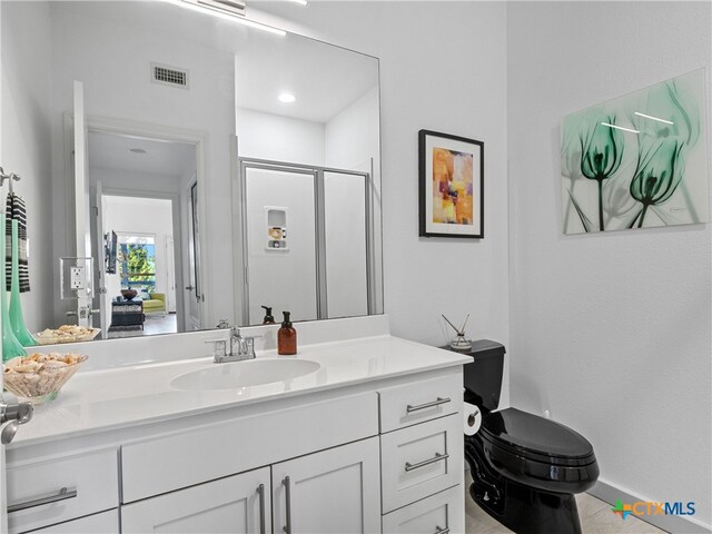 full bathroom with vanity, a shower stall, toilet, and visible vents