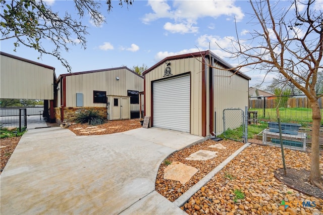 view of outdoor structure with fence, an outbuilding, a gate, and concrete driveway