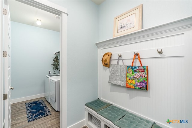 washroom with laundry area, separate washer and dryer, wood finished floors, and baseboards