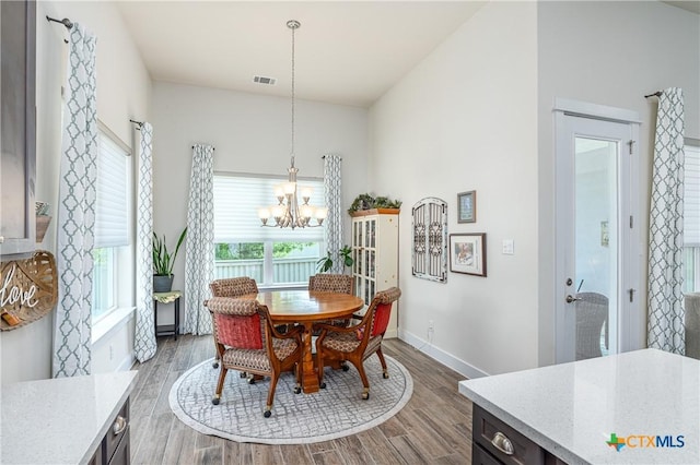 dining room featuring baseboards, dark wood finished floors, visible vents, and a notable chandelier