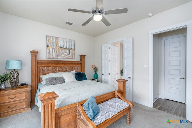 carpeted bedroom featuring a ceiling fan, visible vents, and baseboards