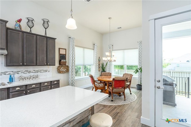 kitchen featuring dark brown cabinetry, visible vents, wood finished floors, decorative light fixtures, and light countertops