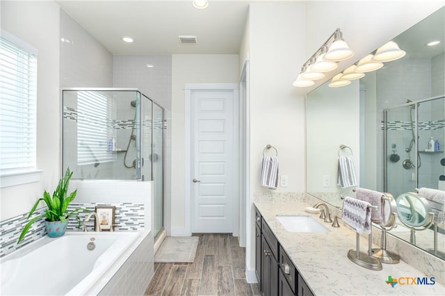 full bath with a stall shower, plenty of natural light, wood finished floors, and vanity