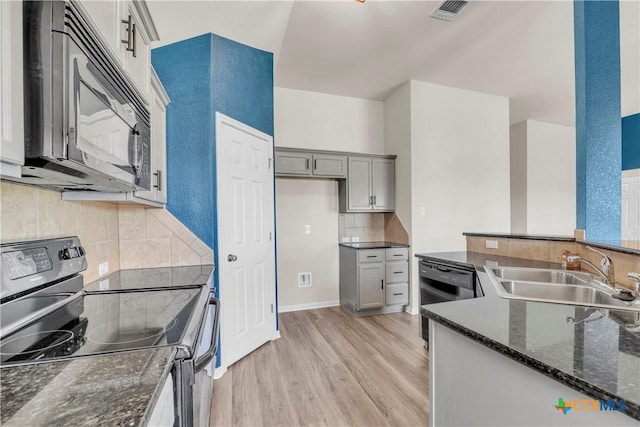 7810 Woodbury Dr, Temple, TX 76502 - kitchen with black appliances, a sink, light wood-type flooring, decorative backsplash, and dark stone counters