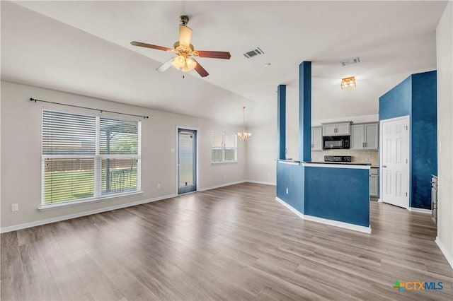 7810 Woodbury Dr, Temple, TX 76502 - unfurnished living room featuring a chandelier, ceiling fan, vaulted ceiling, baseboards, and wood finished floors
