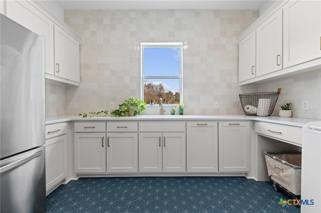 kitchen featuring sink, decorative backsplash, stainless steel fridge, and white cabinets