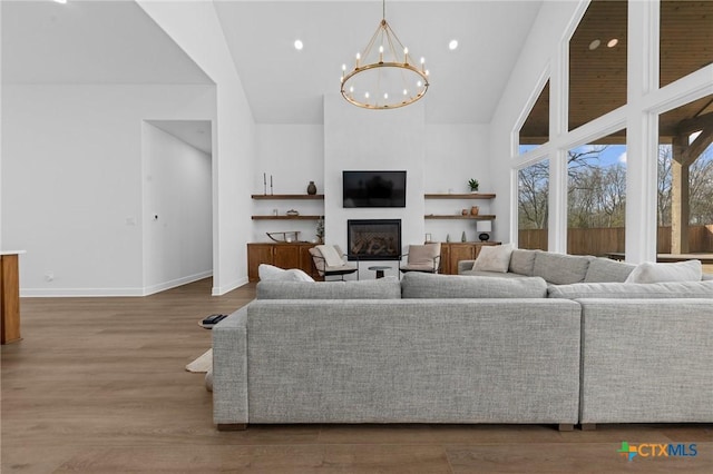 living room with wood-type flooring, an inviting chandelier, and high vaulted ceiling