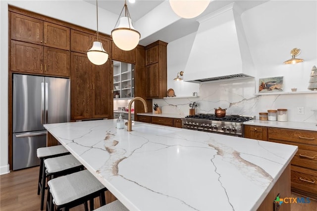 kitchen featuring premium range hood, stainless steel fridge, a kitchen breakfast bar, decorative backsplash, and range