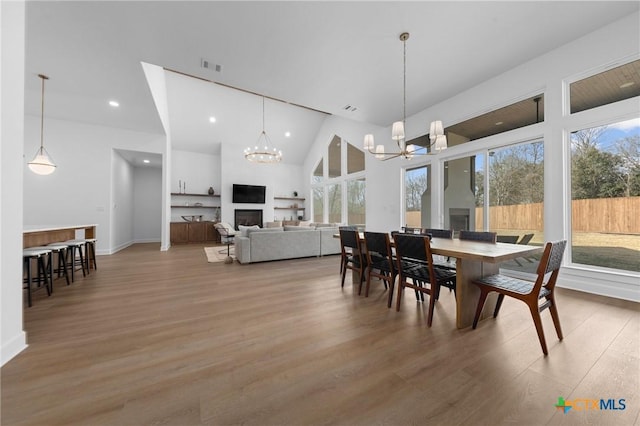 dining room featuring wood-type flooring, a chandelier, and high vaulted ceiling