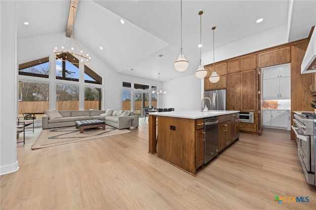 kitchen featuring light hardwood / wood-style flooring, an inviting chandelier, stainless steel appliances, a center island with sink, and decorative light fixtures