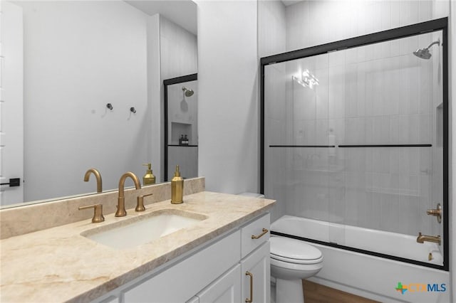 full bathroom featuring vanity, enclosed tub / shower combo, and toilet