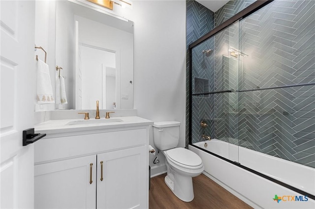 full bathroom featuring vanity, combined bath / shower with glass door, hardwood / wood-style floors, and toilet