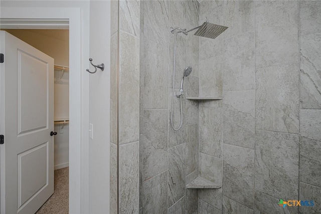 bathroom with tiled shower and a spacious closet