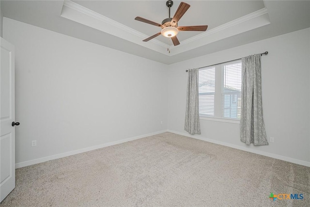 carpeted spare room featuring ornamental molding and a tray ceiling