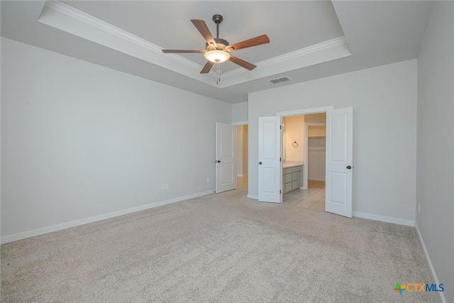 unfurnished bedroom with light carpet, visible vents, baseboards, a tray ceiling, and crown molding