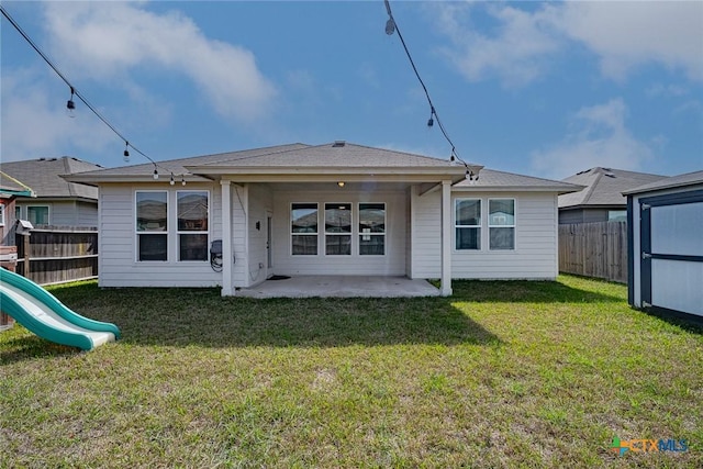 rear view of house featuring a playground, a lawn, a patio area, and a fenced backyard