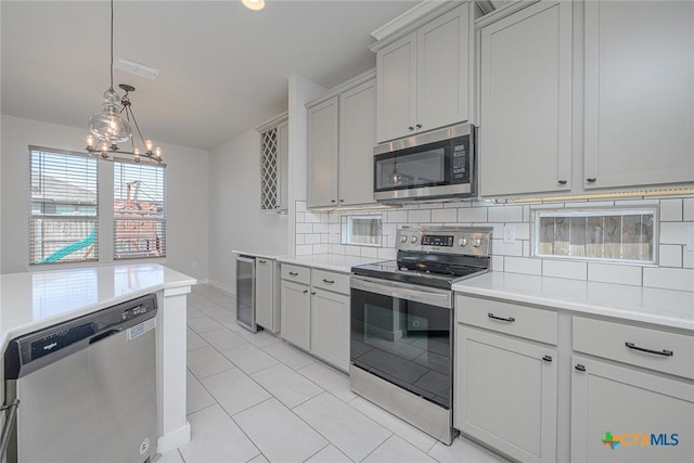 kitchen featuring visible vents, light countertops, appliances with stainless steel finishes, decorative backsplash, and pendant lighting