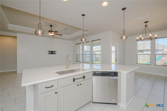 kitchen featuring a sink, light countertops, stainless steel dishwasher, a tray ceiling, and plenty of natural light