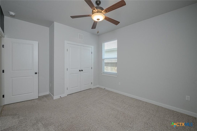 unfurnished bedroom with carpet flooring, a ceiling fan, visible vents, baseboards, and a closet