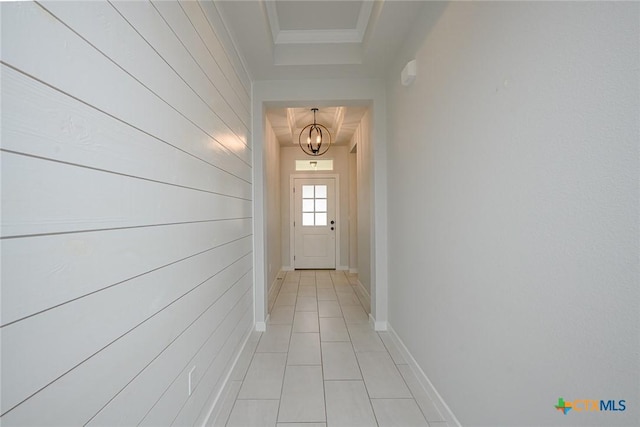 doorway with light tile patterned floors, a notable chandelier, baseboards, ornamental molding, and a raised ceiling