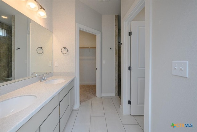 full bathroom featuring double vanity, tile patterned flooring, a sink, and a walk in closet