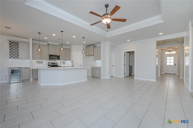 kitchen with gray cabinetry, visible vents, ornamental molding, appliances with stainless steel finishes, and a tray ceiling