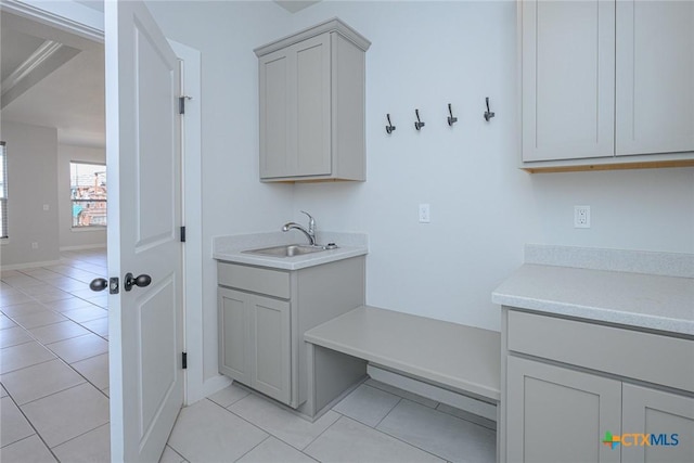 laundry room featuring light tile patterned flooring, a sink, and baseboards