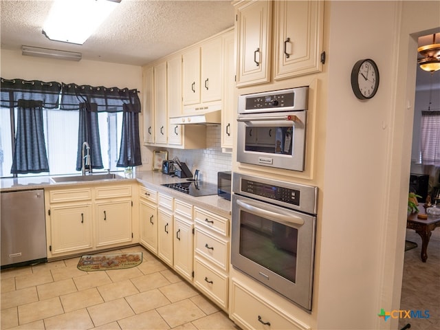 kitchen with black electric cooktop, sink, a textured ceiling, stainless steel dishwasher, and decorative backsplash