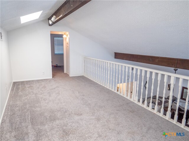 additional living space with vaulted ceiling with skylight, a textured ceiling, and carpet