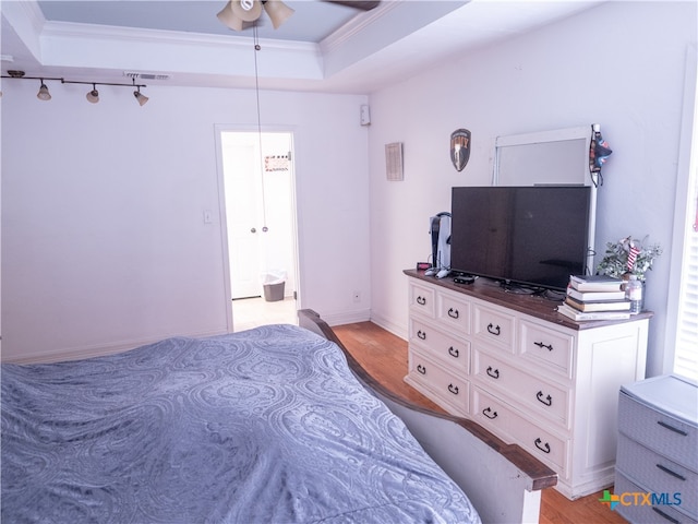 bedroom featuring ceiling fan, a raised ceiling, ornamental molding, and light hardwood / wood-style flooring