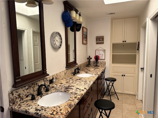 bathroom featuring tile patterned flooring, vanity, and a skylight