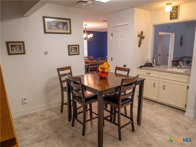 dining space with a chandelier, a textured ceiling, and sink