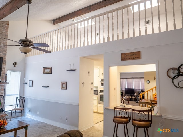 living room with high vaulted ceiling, beamed ceiling, ceiling fan, and a healthy amount of sunlight