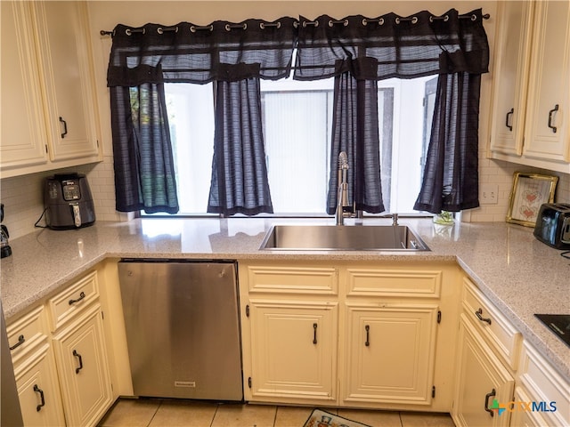 kitchen featuring backsplash, light tile patterned floors, light stone countertops, sink, and stainless steel dishwasher