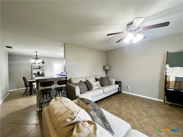 tiled living room featuring ceiling fan with notable chandelier