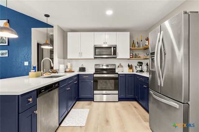 kitchen featuring a peninsula, appliances with stainless steel finishes, blue cabinets, and a sink