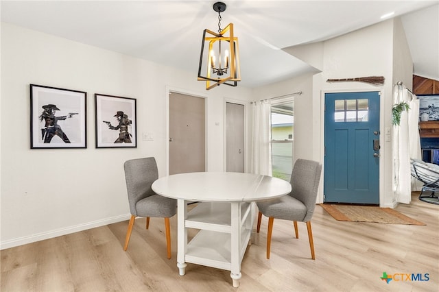 dining space with baseboards, a notable chandelier, and light wood-style floors