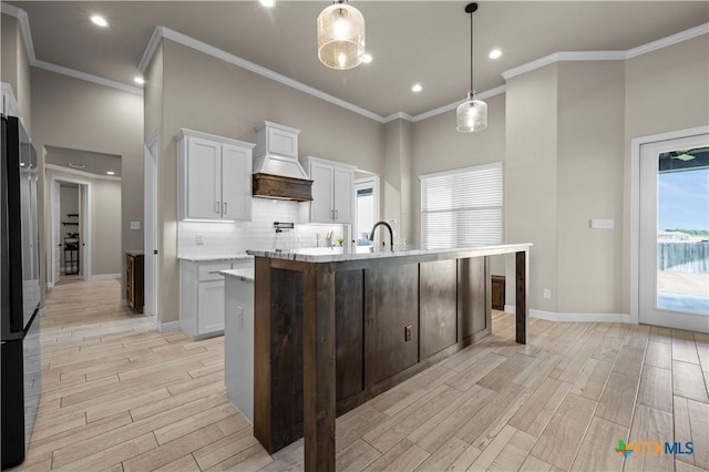 813 Reston Rd, Temple, TX 76502 - kitchen featuring custom range hood, light wood finished floors, freestanding refrigerator, white cabinets, and ornamental molding