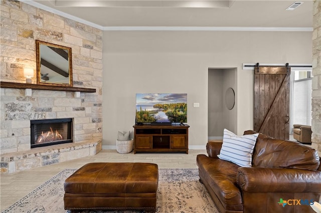 813 Reston Rd, Temple, TX 76502 - living room featuring a barn door, ornamental molding, wood finished floors, and a stone fireplace