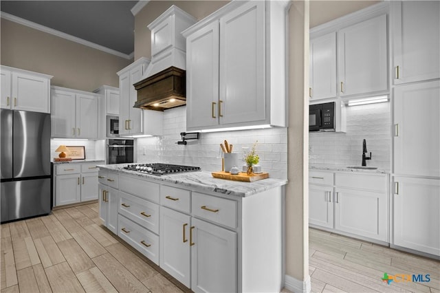 813 Reston Rd, Temple, TX 76502 - kitchen with stainless steel appliances, crown molding, white cabinets, backsplash, and light wood-type flooring