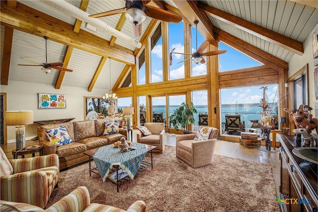 living room with a water view, ceiling fan with notable chandelier, hardwood / wood-style floors, and beamed ceiling