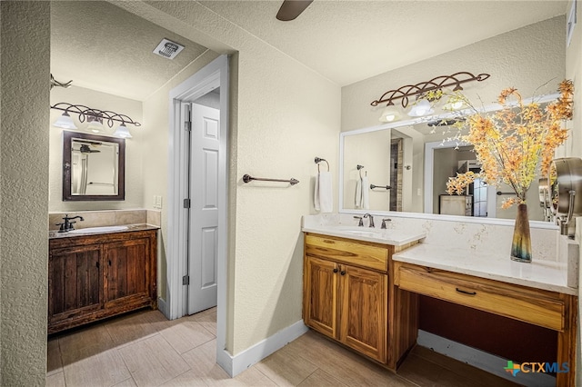 bathroom featuring vanity, ceiling fan, and a textured ceiling