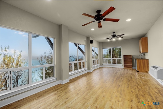 unfurnished living room with sink, a wall mounted AC, and light wood-type flooring